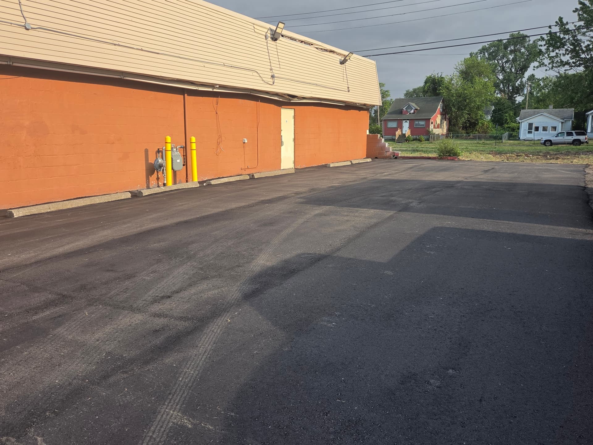 Freshly sealcoated parking lot along an orange brick building before striping