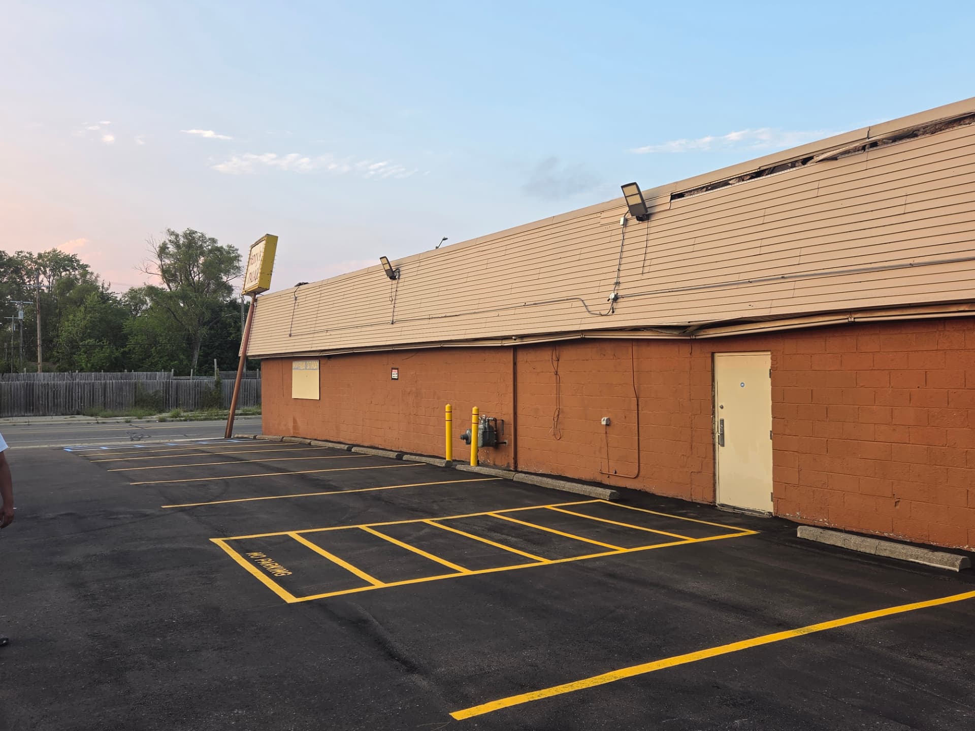 Newly striped stalls and no-parking crosshatch along an orange brick venue wall